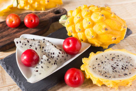 yellow pitahaya or dragon fruit and red plum on wooden backgroundの写真素材