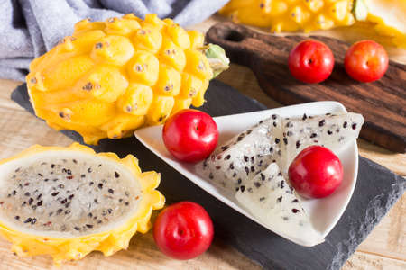 yellow pitahaya or dragon fruit and red plum on wooden backgroundの写真素材