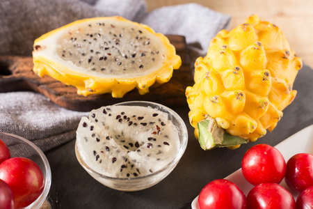 yellow pitahaya or dragon fruit and red plum on wooden backgroundの写真素材