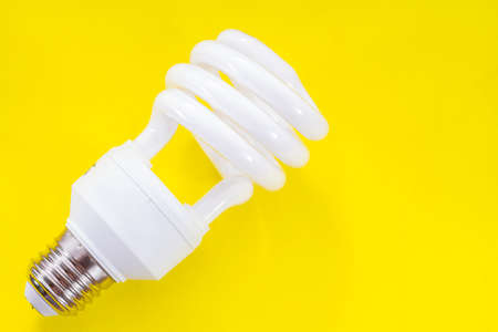 Fluorescent light bulb on yellow background, technology that contains polluting gasesの写真素材