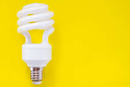 Fluorescent light bulb on yellow background, technology that contains polluting gasesの写真素材