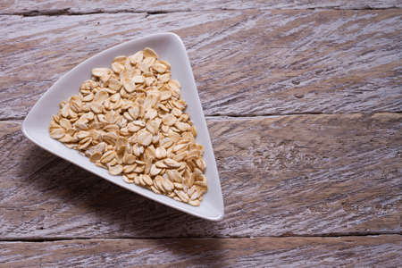 oat flakes in white bowl on wooden tableの写真素材