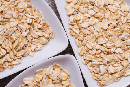 oat flakes in white bowl on wooden tableの写真素材