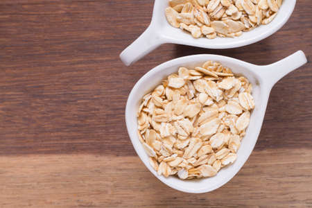 oat flakes in white bowl on wooden tableの写真素材
