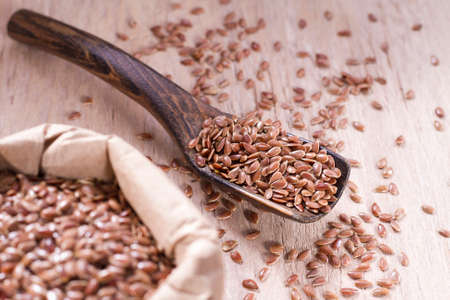 linseed seeds in container and spoon on the table.の写真素材