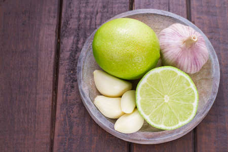 garlic and lemon in bowl on wooden table.の写真素材
