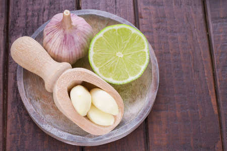 garlic and lemon in bowl on wooden table.の写真素材