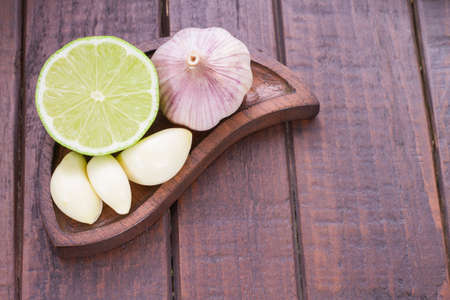 garlic and lemon in bowl on wooden table.の写真素材