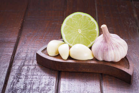 garlic and lemon in bowl on wooden table.の写真素材