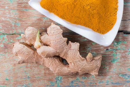 Turmeric powder and ginger root on old wood, top viewの写真素材