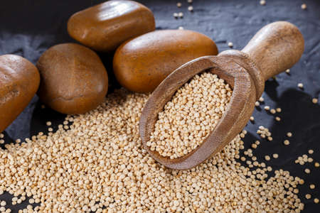 Quinoa grains with spoon and bowl on black backgroundの写真素材
