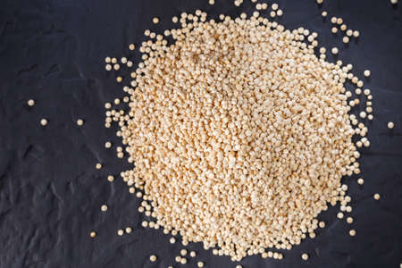Quinoa grains with spoon and bowl on black backgroundの写真素材