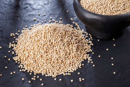 Quinoa grains with spoon and bowl on black backgroundの写真素材