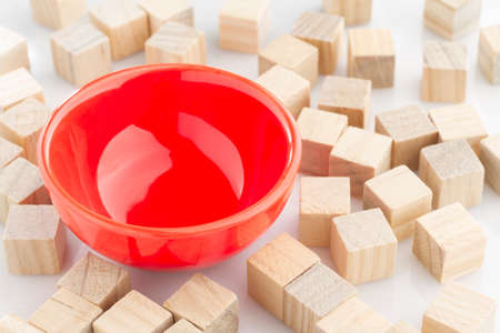 red bowl surrounded by wooden blocks on white background.