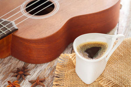 cup of coffee and ukulele on rustic woodの写真素材