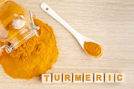 turmeric powder in glass bowl on wood- curcuma longa