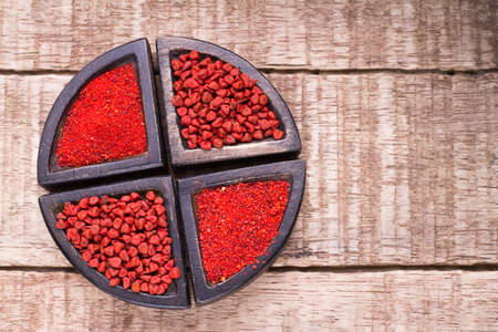 Annatto beans and powder in bowl on the table
