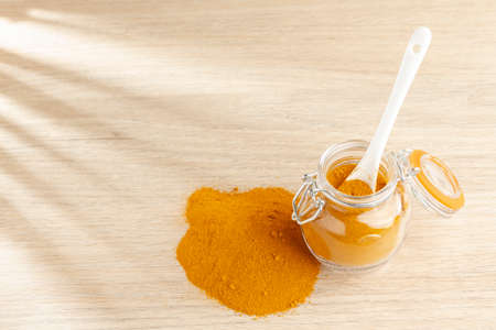 turmeric powder in glass bowl on wood- curcuma longa