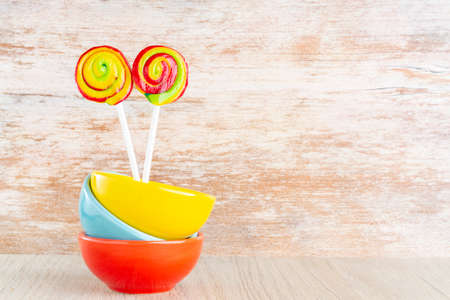 lollipops and colorful pots on wooden background, close-upの写真素材