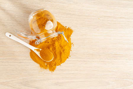 turmeric powder in glass bowl on wood- curcuma longa