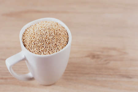 White cup filled with quinoa grains on wooden backgroundの写真素材