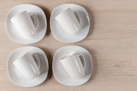 White ceramic cups and plates on wooden background, imageの写真素材