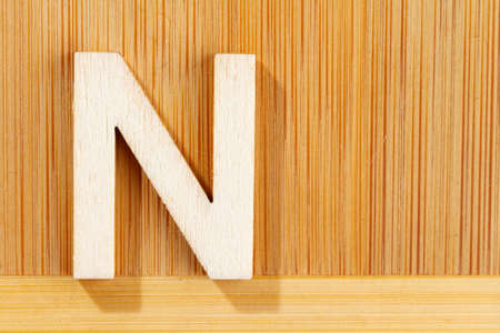 Letter N of wood-made alphabet, top view and space for text