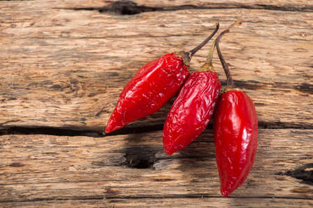 three red chili peppers on rustic wooden backgroundの写真素材