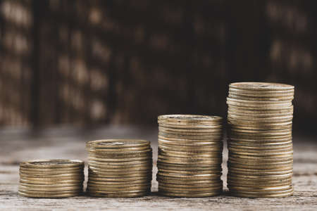 Stacks of coins growing, on old wood