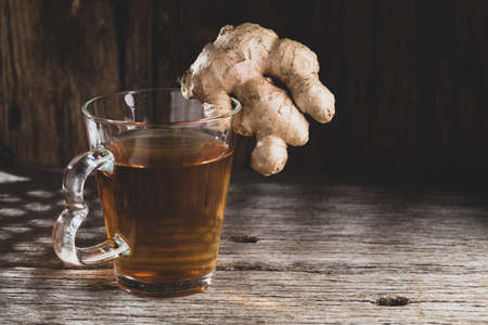 Glass with ginger tea on old wood, space for textの写真素材