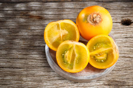 Fruit of lulo or naranjilla on wood subtropical perennial plant of northwestern South America, close-up image, Solanum quitoenseの写真素材