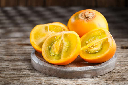 Fruit of lulo or naranjilla on wood subtropical perennial plant of northwestern South America, close-up image, Solanum quitoenseの写真素材
