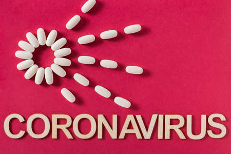 Coronavirus word written with wooden letters and medicine tablets, top view
