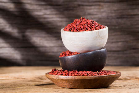 annatto seeds in bowl on wooden backgroundの写真素材