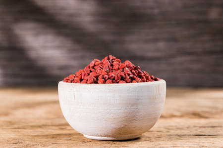annatto seeds in bowl on wooden backgroundの写真素材