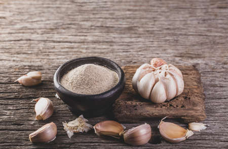 garlic and garlic powder on old wood, close up imageの写真素材