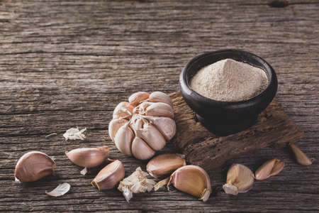 garlic and garlic powder on old wood, close up imageの写真素材