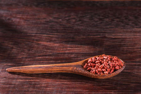 Annatto seeds in bowl on wooden background - Bixa Orellana.の写真素材