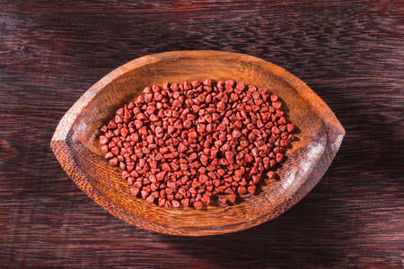 Annatto seeds in bowl on wooden background - Bixa Orellana.の写真素材