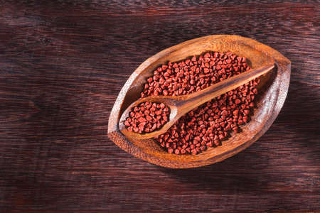 Annatto seeds in bowl on wooden background - Bixa Orellana.の写真素材