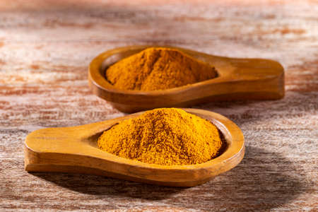 Turmeric powder in bowl on wooden background (Curcuma longa)