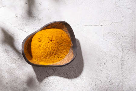 turmeric powder in wooden bowl on white background (Curcuma longa)の写真素材