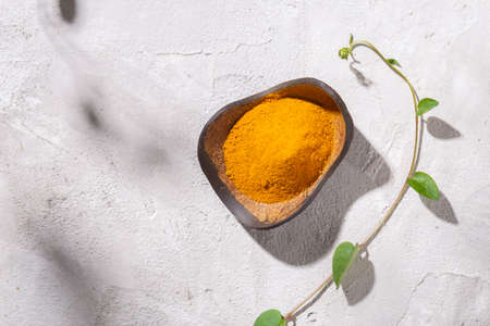 turmeric powder in wooden bowl on white background (Curcuma longa)の写真素材