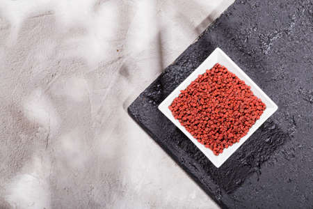 achiote grains in wooden bowl on white background (Bixa orellana)の写真素材