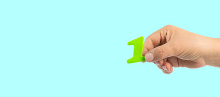 Woman's hand holding plastic number 1 symbol, close up imageの写真素材