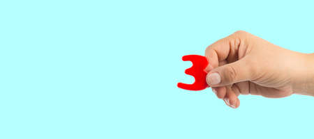 Woman's hand holding plastic number 3 symbol, close up imageの写真素材