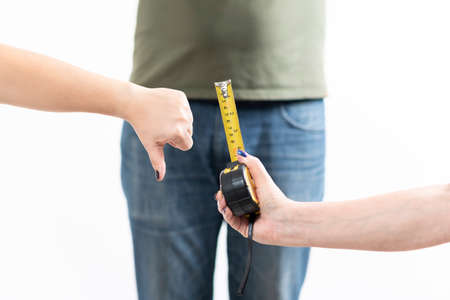 woman's hands disapproving of penis size, compared to a tape measure