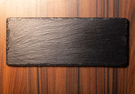 black stone on wooden background, space for text