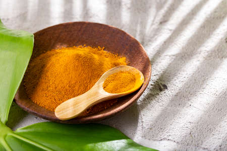 Turmeric powder, in wooden bowl and spoon (curcuma longa)の写真素材
