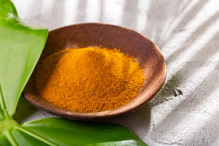 Turmeric powder, in wooden bowl and spoon (curcuma longa)の写真素材